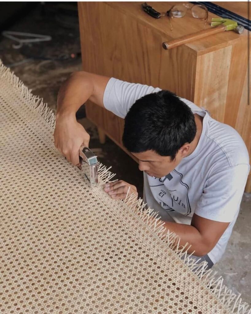 Workers installing plastic cane webbing sheets on furniture frames