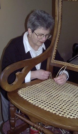Technician replacing classic rattan chair strands Close-up of professional chair cane replacement process